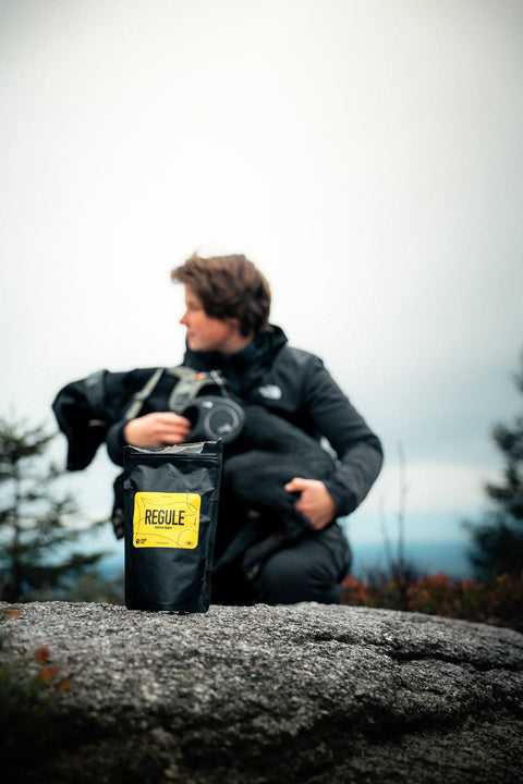 Regule dog treat pouch standing on a rock, with girl and her black labrador blurred behind in the background